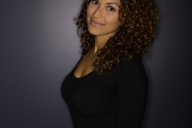 A woman in a black dress smiles. 